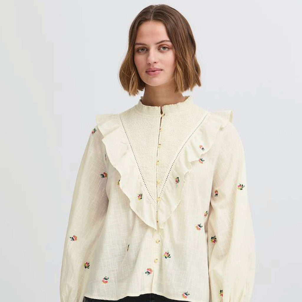 Cream-colored Atelier Reve Birch Olivia Blouse with floral embroidery and ruffle details.