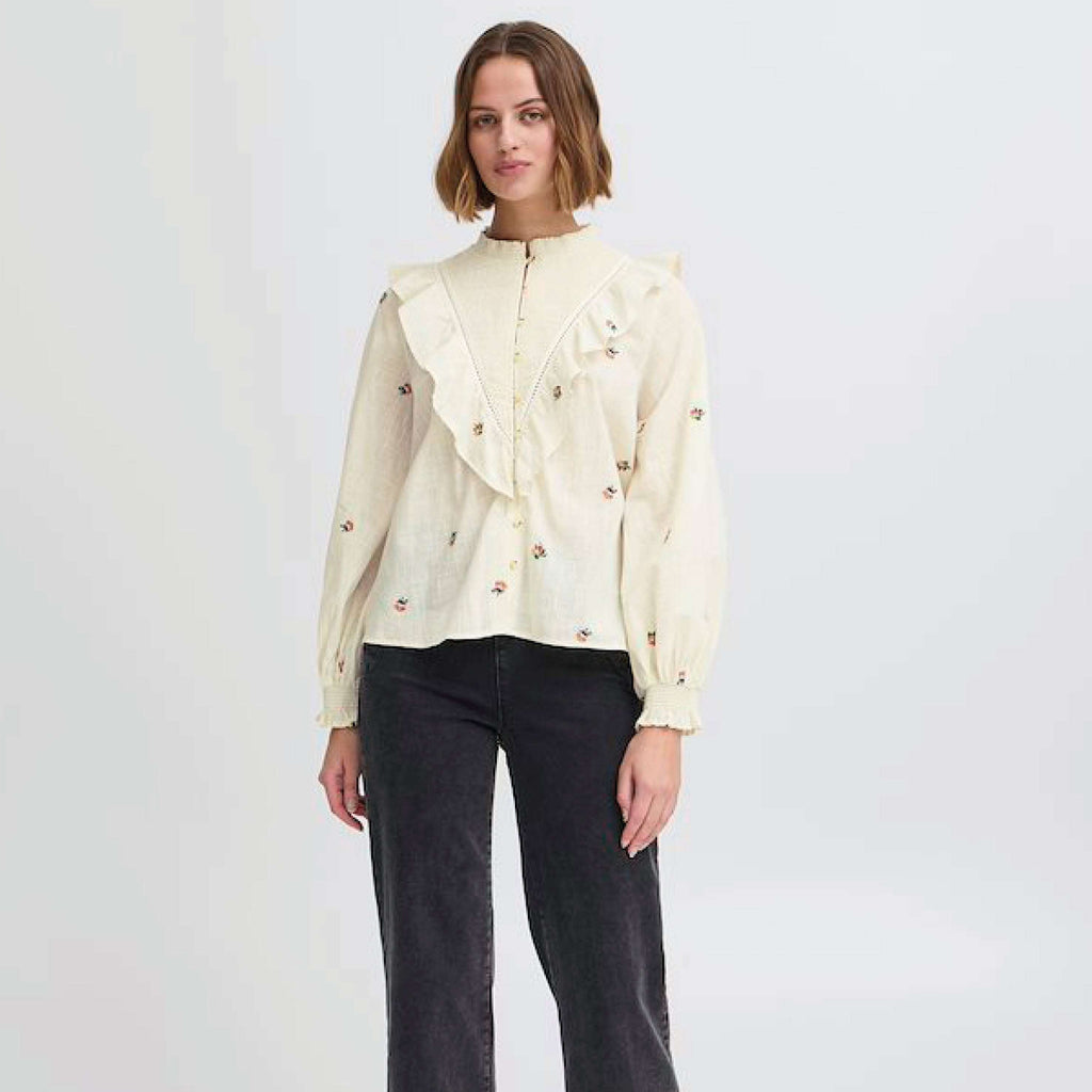 Cream floral-embroidered blouse with ruffles and long sleeves by Atelier Reve.