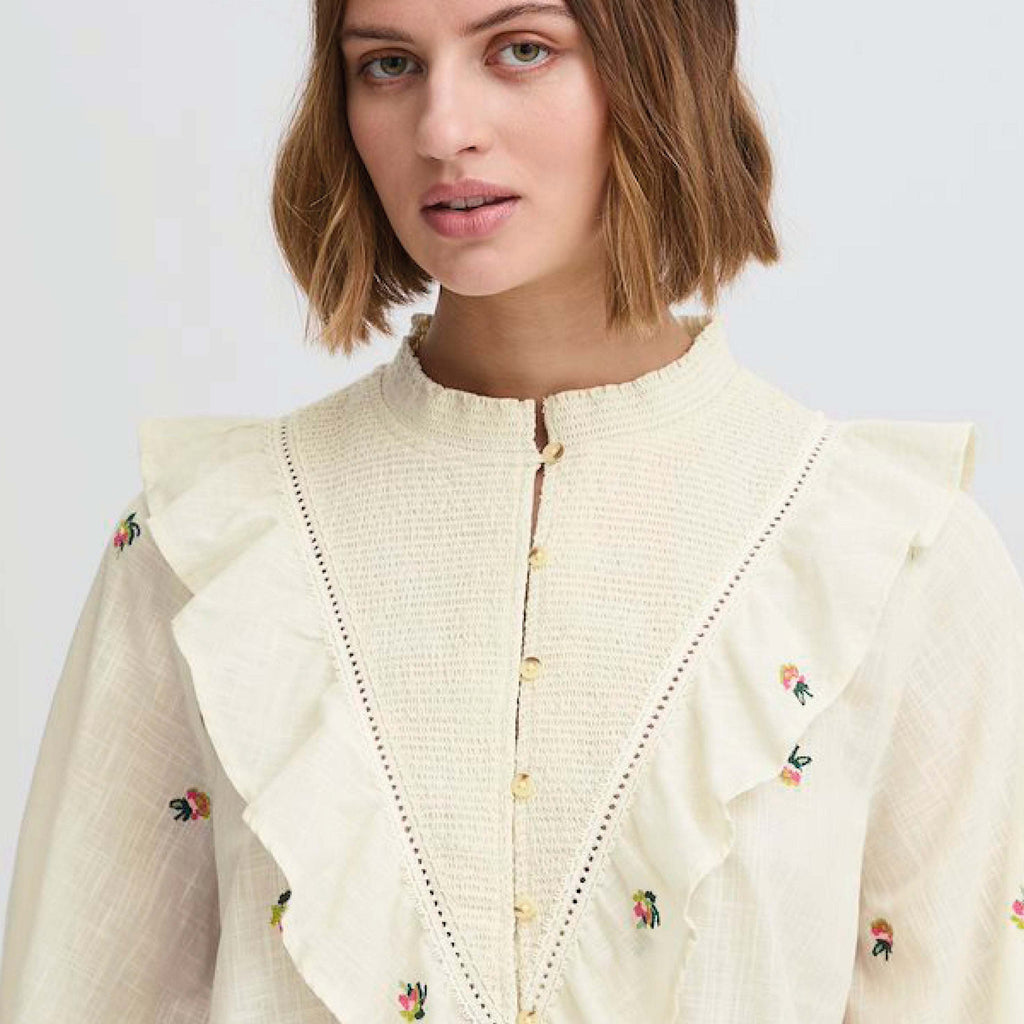 Cream-colored Atelier Reve Birch Olivia Blouse with floral embroidery and ruffle details.