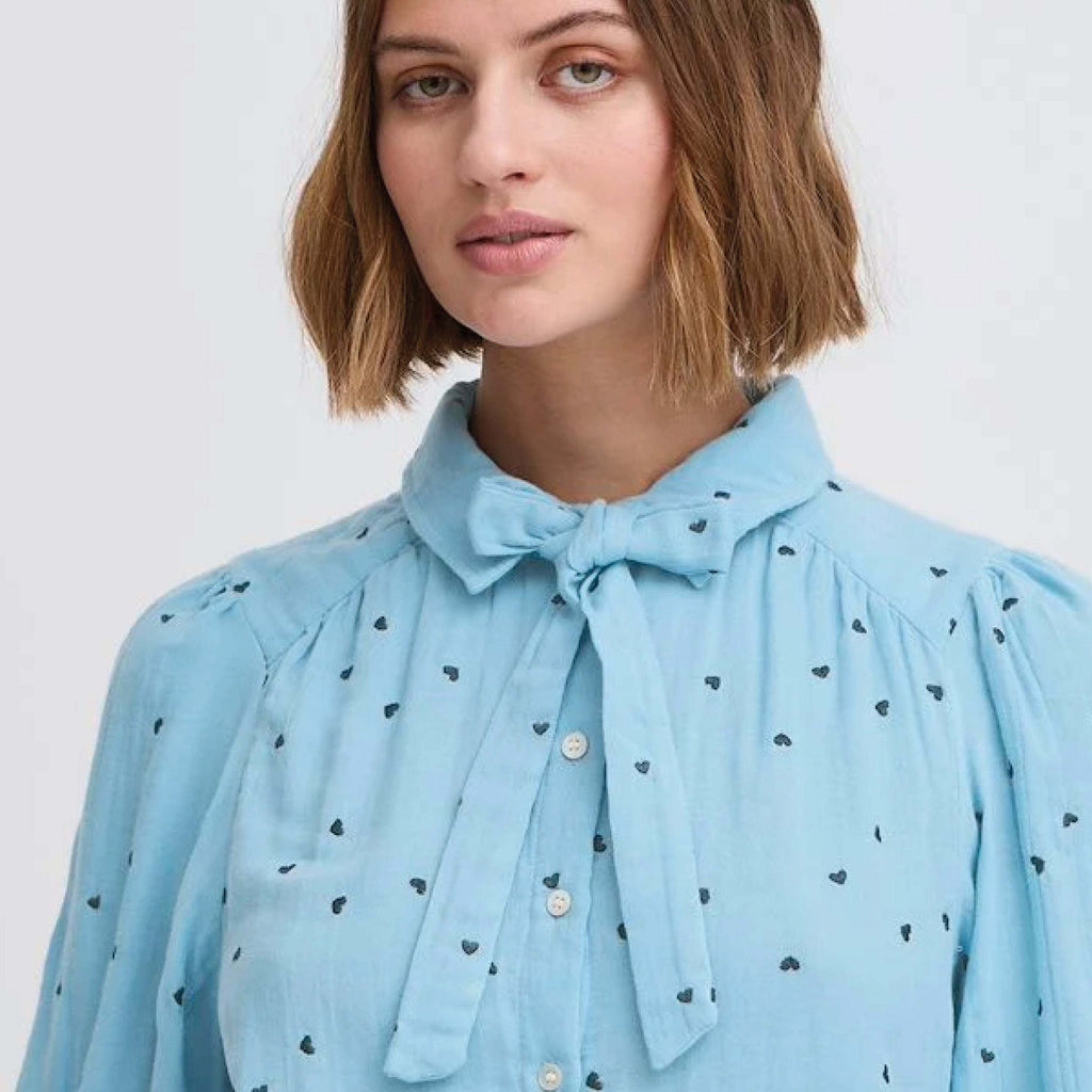 Pale blue heart-embroidered Camilo Blouse by Atelier Rêve with removable tie and elasticated half-length sleeves.