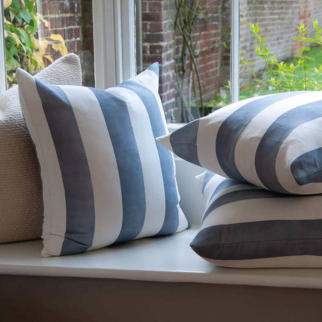 Blue Riviera Striped Linen Cushion on a window seat showcasing wide blue and white stripes in organic linen-cotton blend.