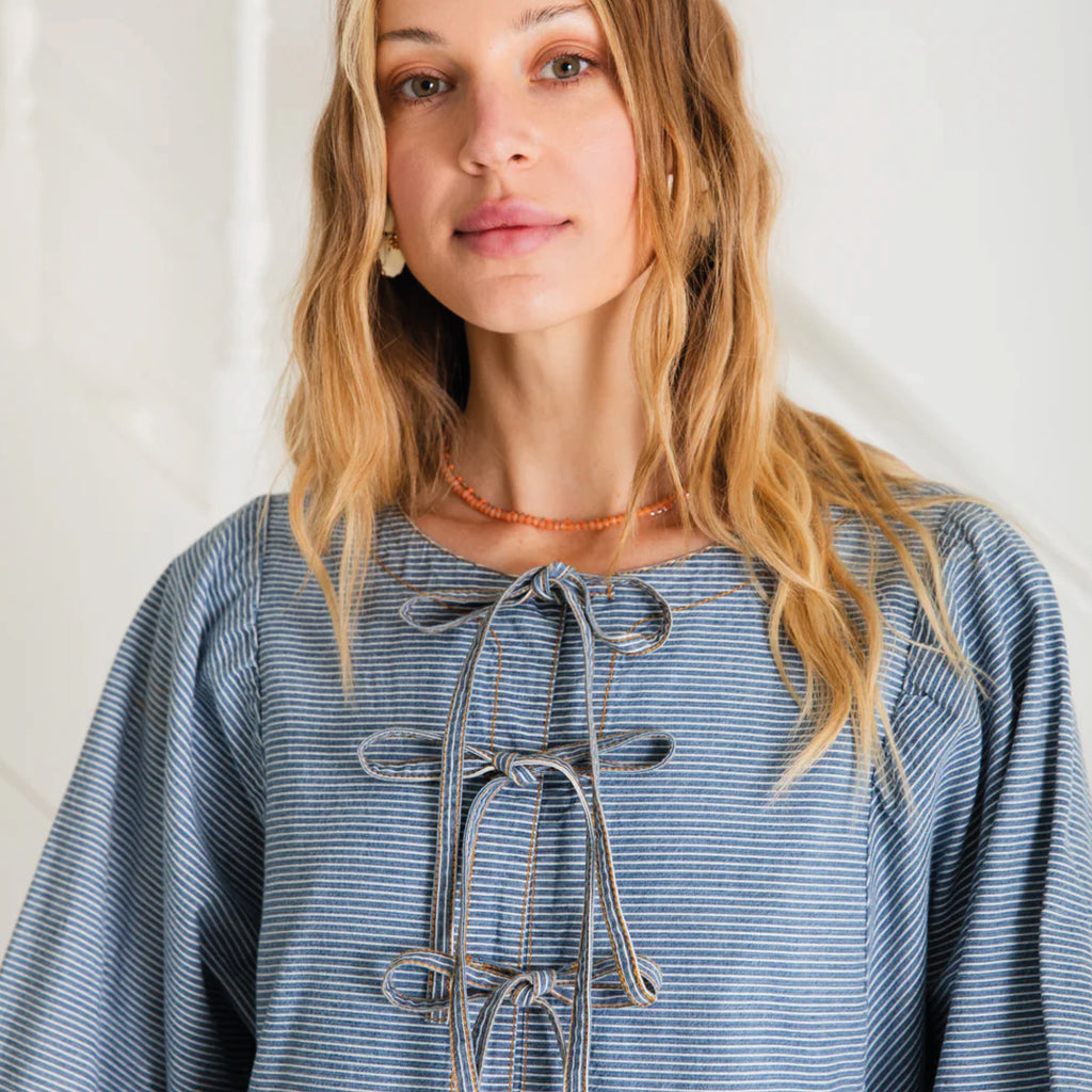 Relaxed easy-fit organic self stripe blue cotton dress with a bow fastening detail and an empire line.
Bonté Blue Amber Dress - Jo And Co Bonté Blue Amber Dress - Bonté