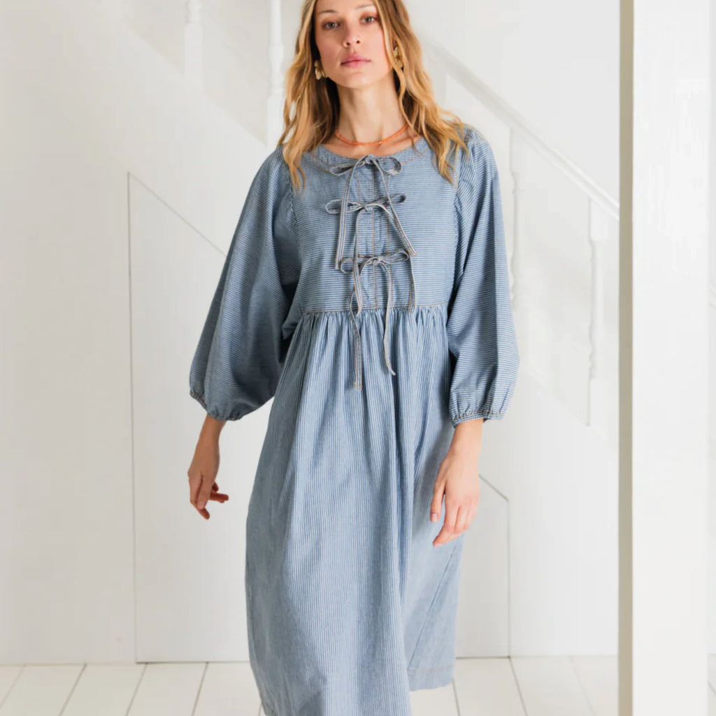 Relaxed easy-fit organic self stripe blue cotton dress with a bow fastening detail and an empire line.
Bonté Blue Amber Dress - Jo And Co Bonté Blue Amber Dress - Bonté