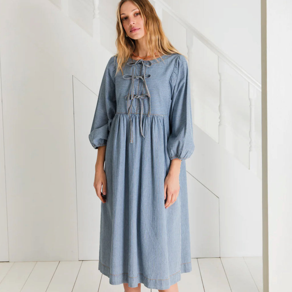 Relaxed easy-fit organic self stripe blue cotton dress with a bow fastening detail and an empire line.
Bonté Blue Amber Dress - Jo And Co Bonté Blue Amber Dress - Bonté