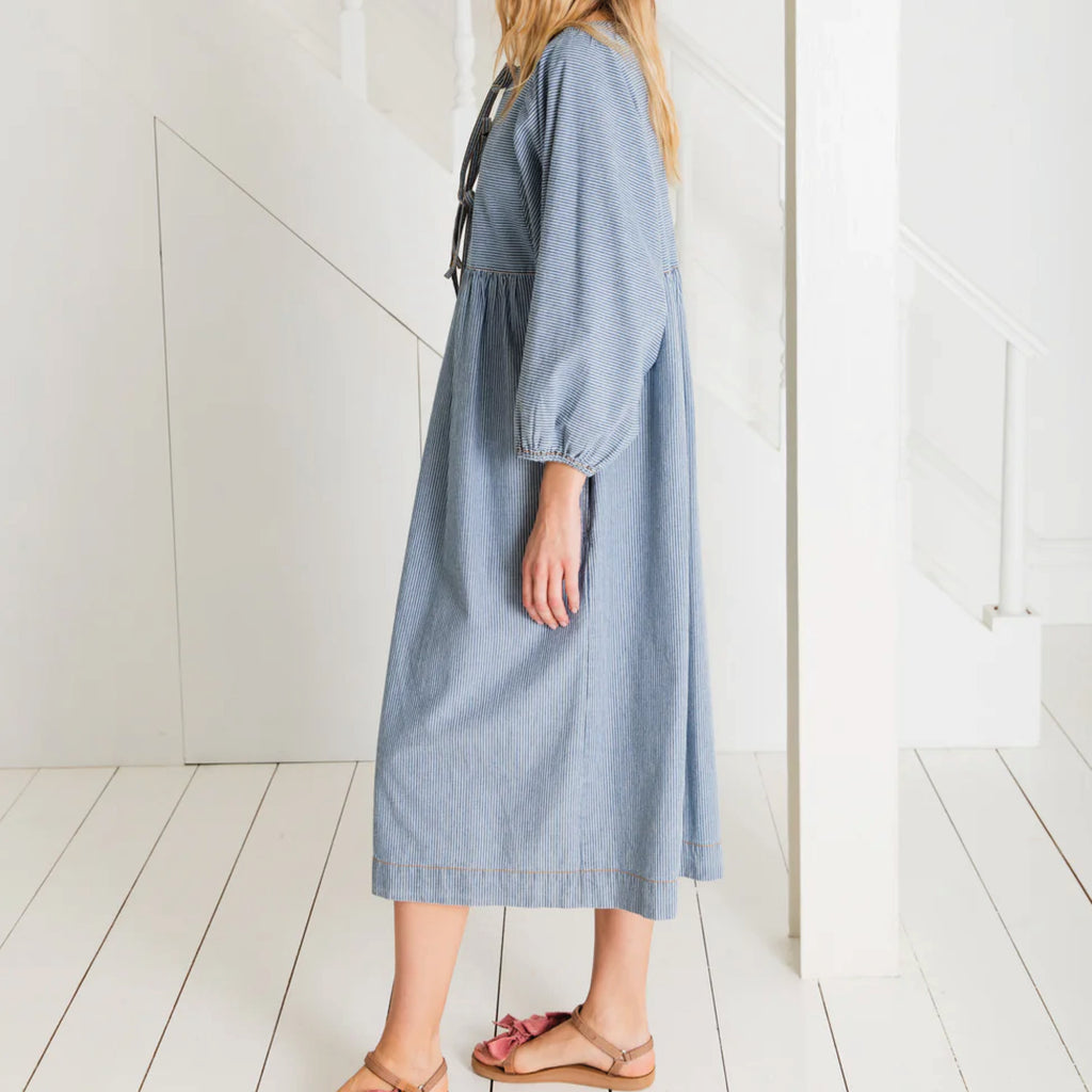 Relaxed easy-fit organic self stripe blue cotton dress with a bow fastening detail and an empire line.
Bonté Blue Amber Dress - Jo And Co Bonté Blue Amber Dress - Bonté