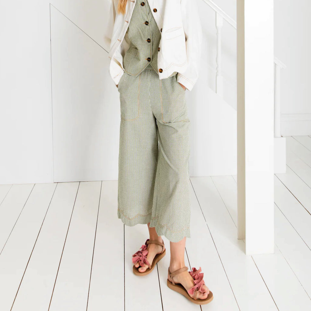 Relaxed fitting three-quarter length wide leg trouser in green cotton seersucker gingham with an elasticated back and scallop hem.
Bonté Green Gingham Aide Trousers - Jo And Co Bonté Green Gingham Aide Trousers - Bonté