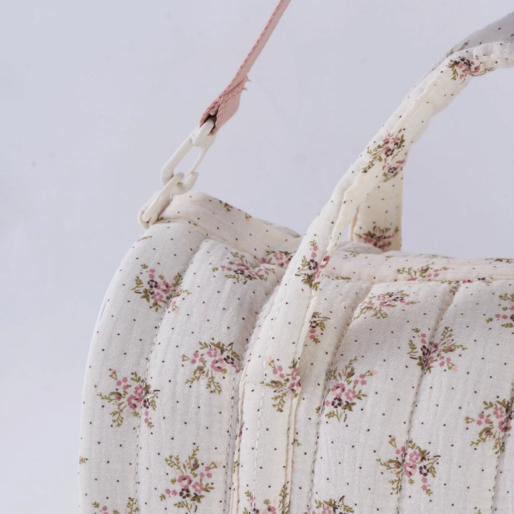 Crepe fabric duffle bag with pink roses print on cream cotton quilted fabric with handles and adjustable pink shoulder strap.
Lilac Floral Duffle Bag - Jo And Co Lilac Floral Duffle Bag