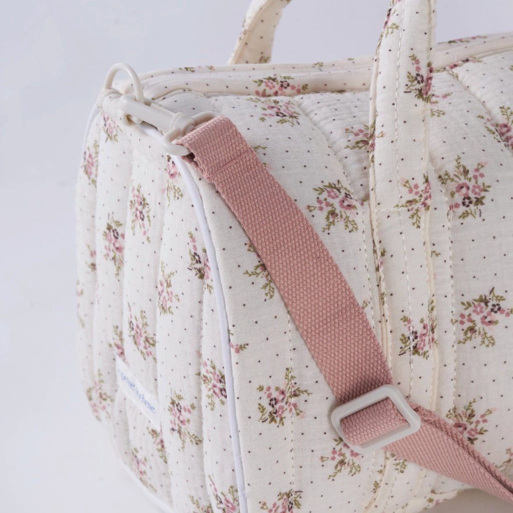 Crepe fabric duffle bag with pink roses print on cream cotton quilted fabric with handles and adjustable pink shoulder strap.
Lilac Floral Duffle Bag - Jo And Co Lilac Floral Duffle Bag