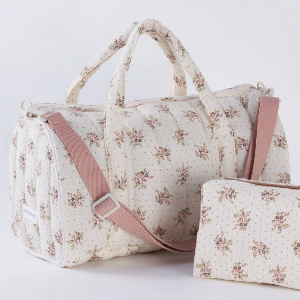 Crepe fabric duffle bag with pink roses print on cream cotton quilted fabric with handles and adjustable pink shoulder strap.
Lilac Floral Duffle Bag - Jo And Co Lilac Floral Duffle Bag