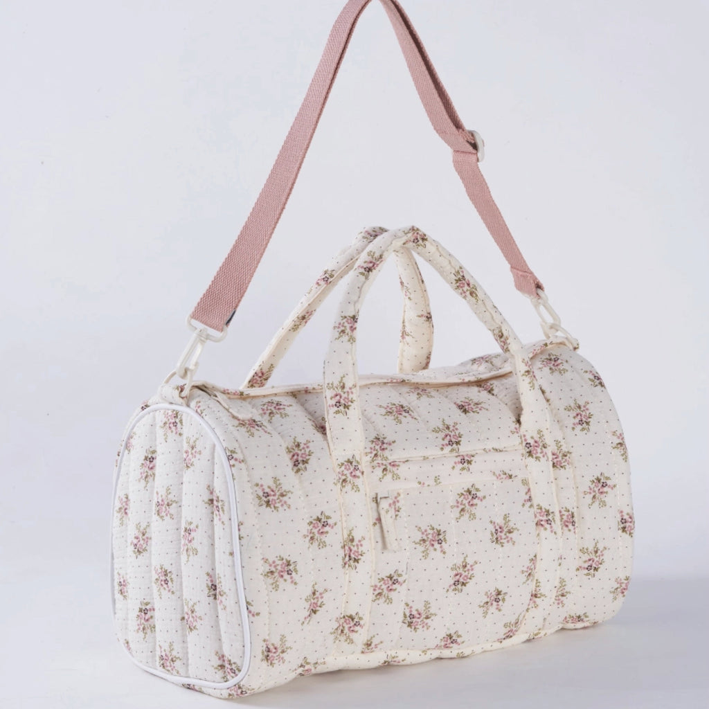 Crepe fabric duffle bag with pink roses print on cream cotton quilted fabric with handles and adjustable pink shoulder strap.
Lilac Floral Duffle Bag - Jo And Co Lilac Floral Duffle Bag