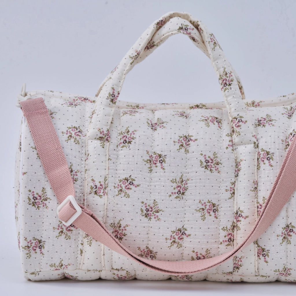 Crepe fabric duffle bag with pink roses print on cream cotton quilted fabric with handles and adjustable pink shoulder strap.
Lilac Floral Duffle Bag - Jo And Co Lilac Floral Duffle Bag