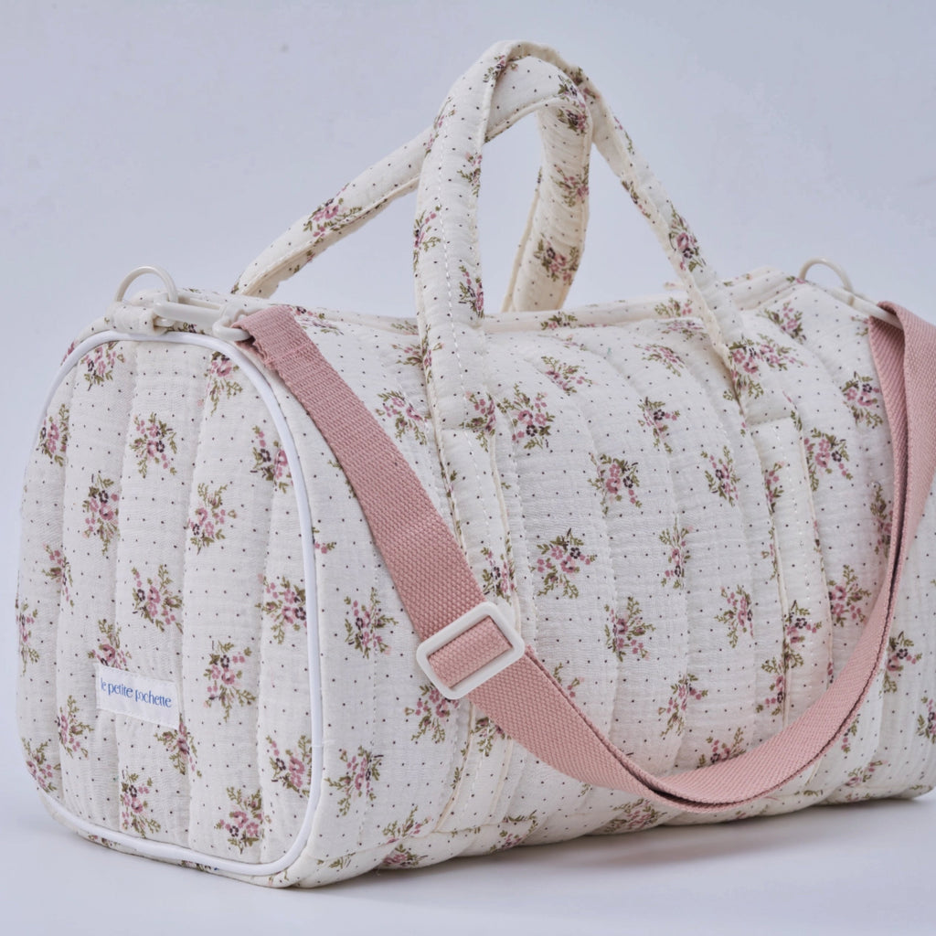 Crepe fabric duffle bag with pink roses print on cream cotton quilted fabric with handles and adjustable pink shoulder strap.
Lilac Floral Duffle Bag - Jo And Co Lilac Floral Duffle Bag