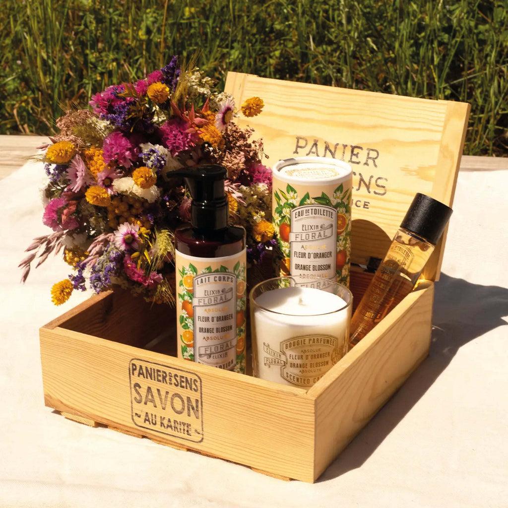 Panier Des Sens Orange Blossom Scented Candle 180g in a wooden gift box with floral arrangement.