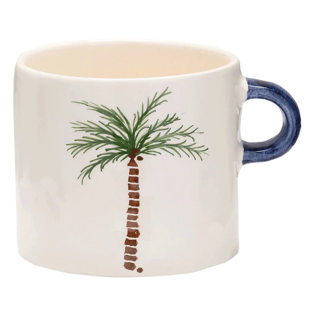 Ceramic white mug with hand painted palm tree and blue painted handle.
Palm Tree Mug - Jo And Co Palm Tree Mug - Anna + Nina