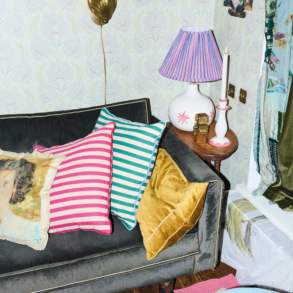 Pink Radiant Candle Holder on side table near a beige sofa with colorful cushions in a cozy living room setting.