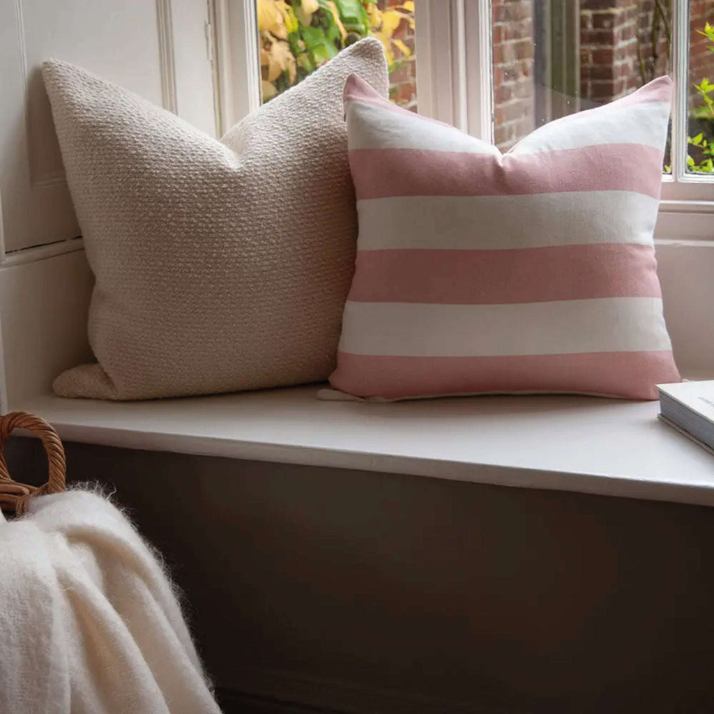 Pink Riviera Striped Linen Cushion with wide stripes on a window seat, made from organic linen and cotton blend for elegant home decor.