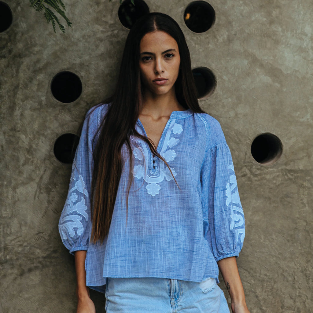 Blue blouse in cotton mélange, with appliqué motifs and decorative stitching in white. Elasticated blouson three-quarter length sleeves.
Rose And Rose Blue & White Oval Blouse - Jo And Co Rose And Rose Blue & White Oval Blouse - Rose And Rose