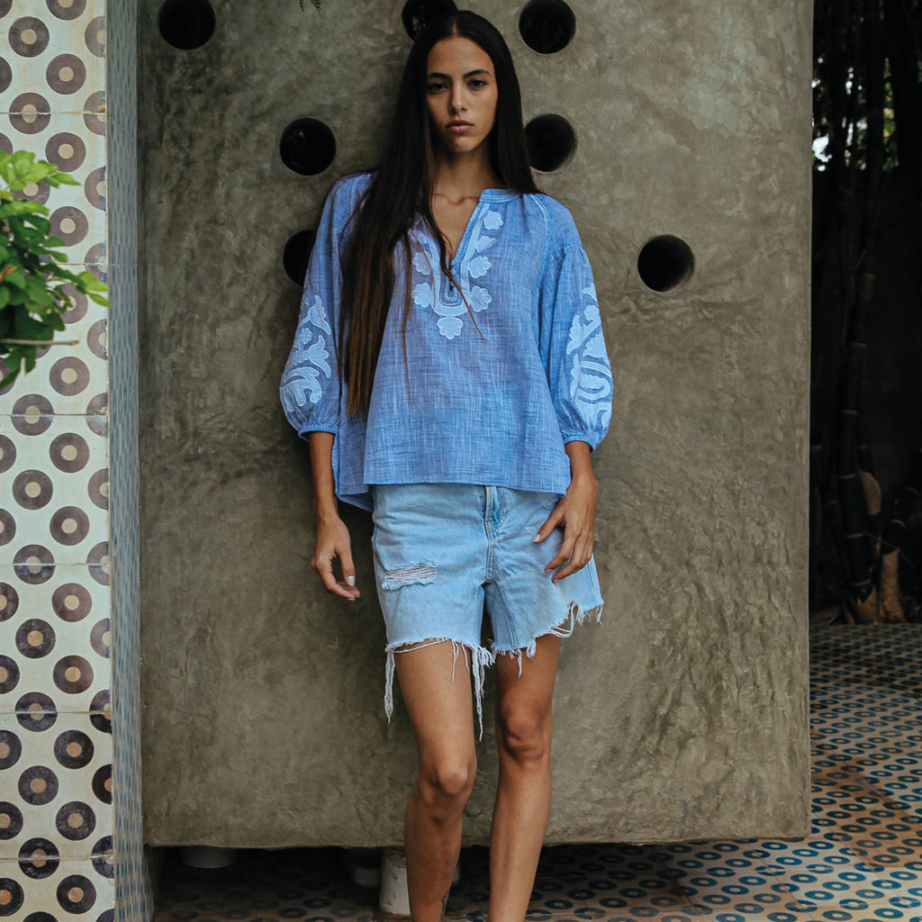 Blue blouse in cotton mélange, with appliqué motifs and decorative stitching in white. Elasticated blouson three-quarter length sleeves.
Rose And Rose Blue & White Oval Blouse - Jo And Co Rose And Rose Blue & White Oval Blouse - Rose And Rose