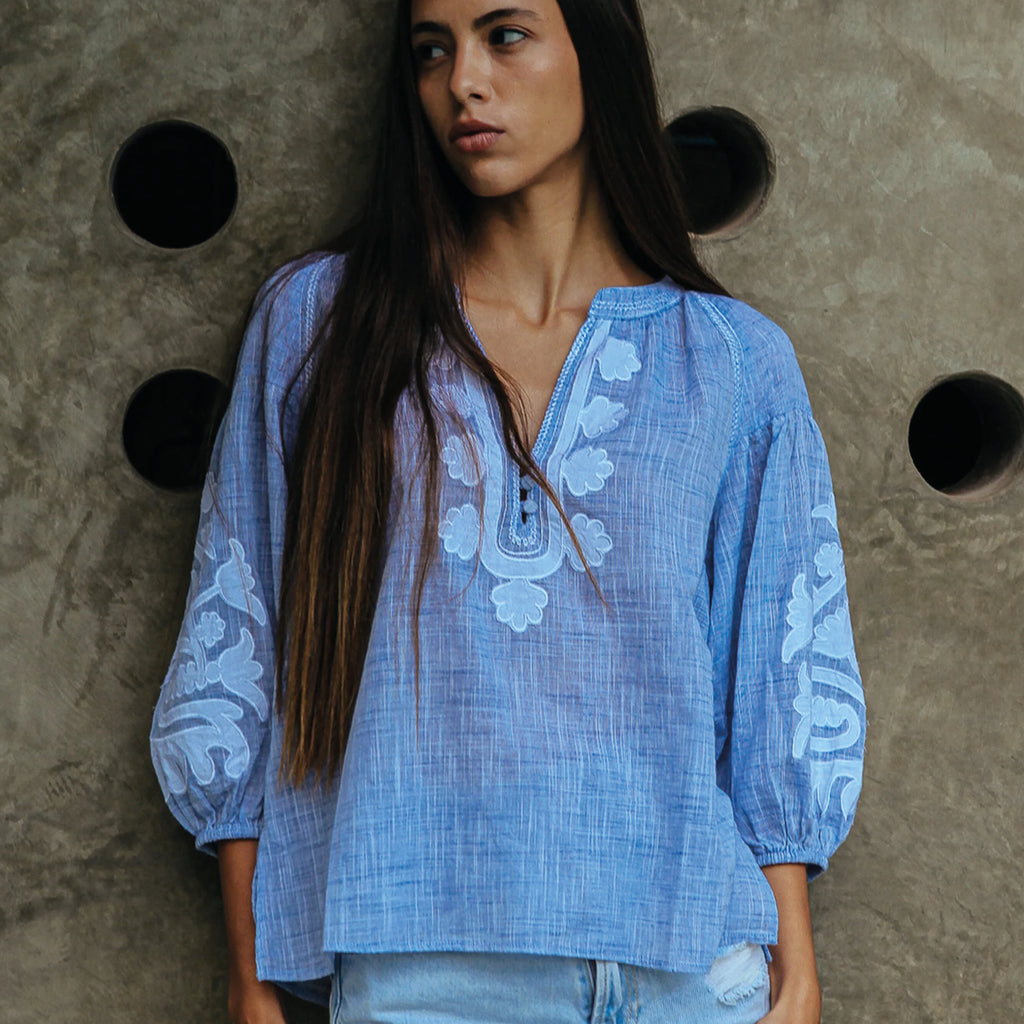 Blue blouse in cotton mélange, with appliqué motifs and decorative stitching in white. Elasticated blouson three-quarter length sleeves.
Rose And Rose Blue & White Oval Blouse - Jo And Co Rose And Rose Blue & White Oval Blouse - Rose And Rose