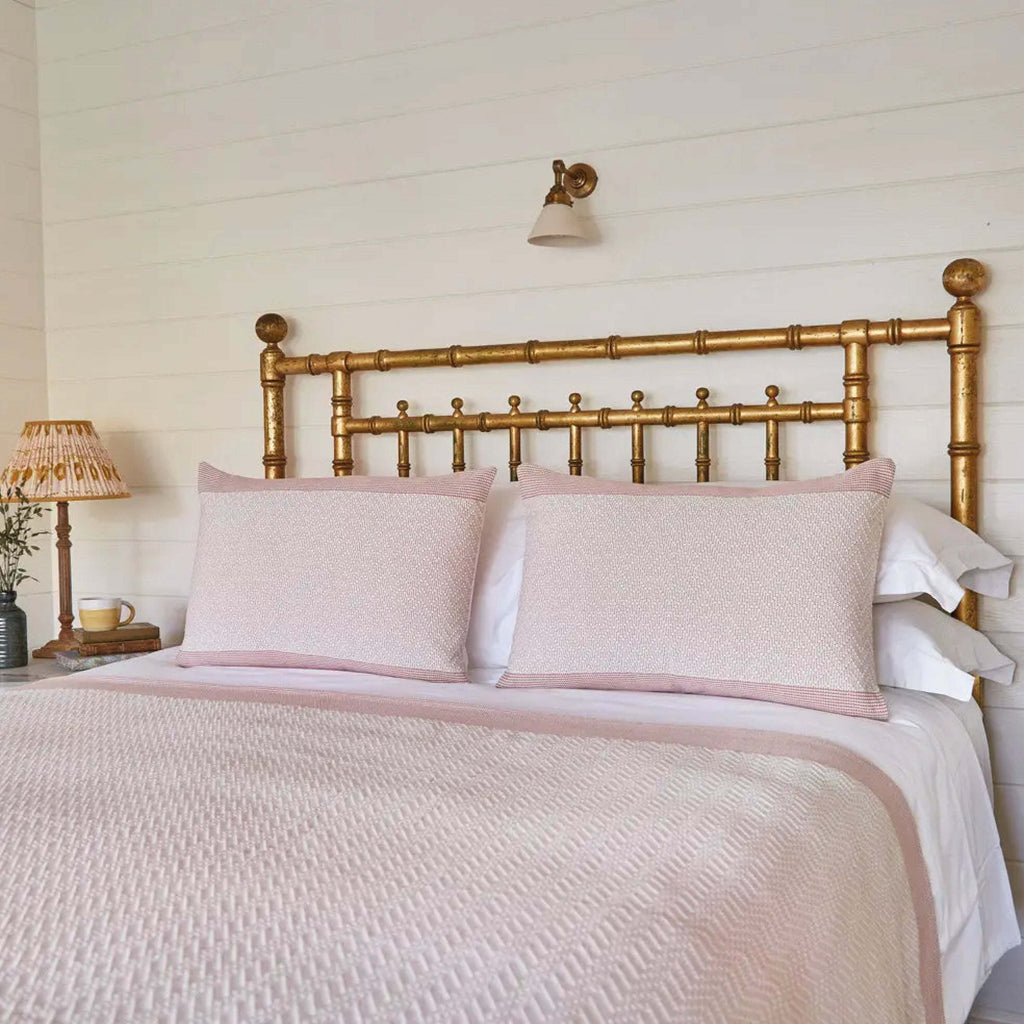 Rose Pink Chevron Cushion on a bed with white linen featuring raised chevron embroidery detail.