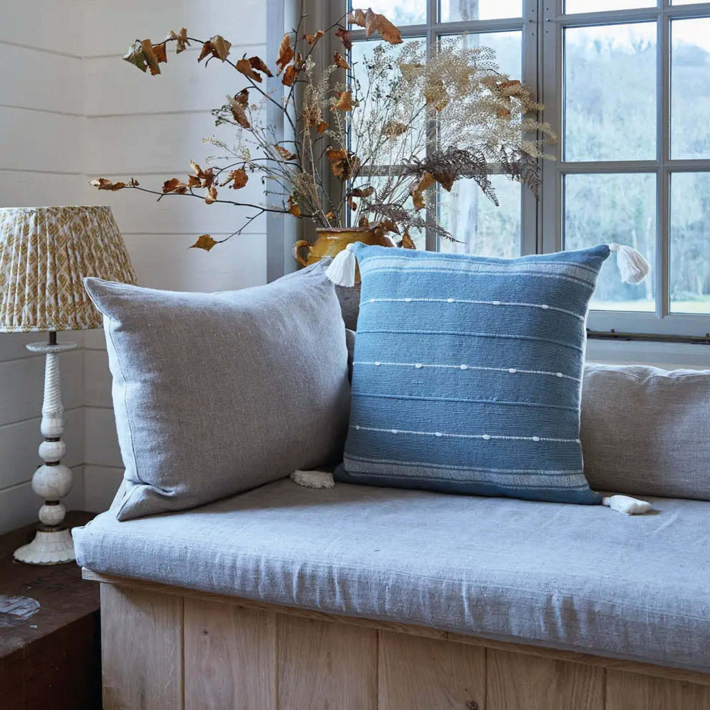 Sky Blue Tassel Cushion with soft tassels and discreet striped design on a sofa.