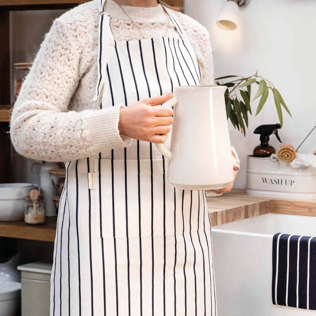 Warm White Bampton Apron with stripes and front pocket in a kitchen setting.